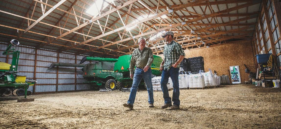 Two farmers walking inside barn