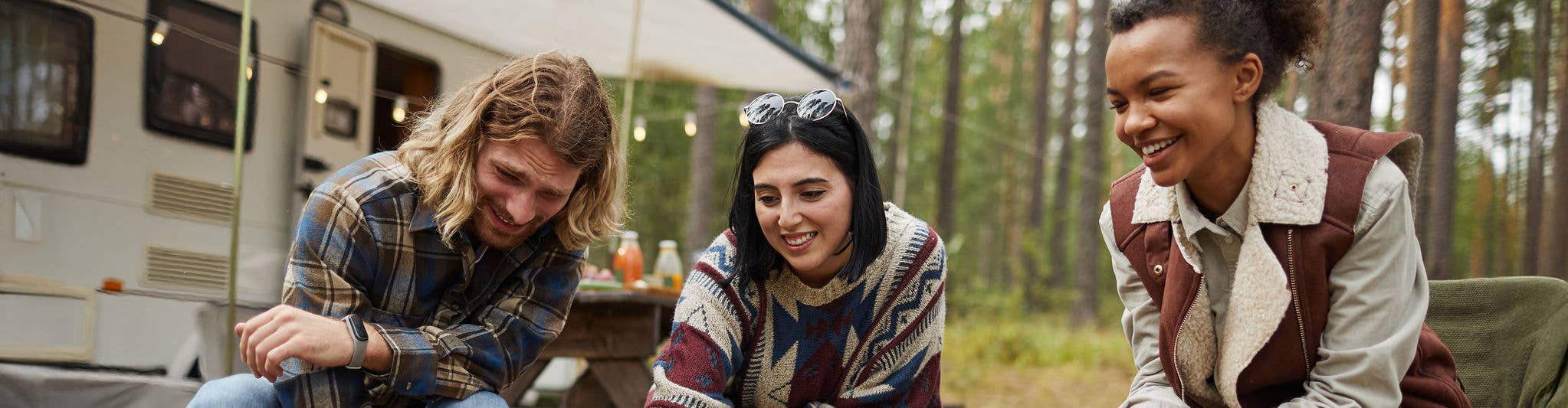 Friends camping in an RV, gathered around a campfire