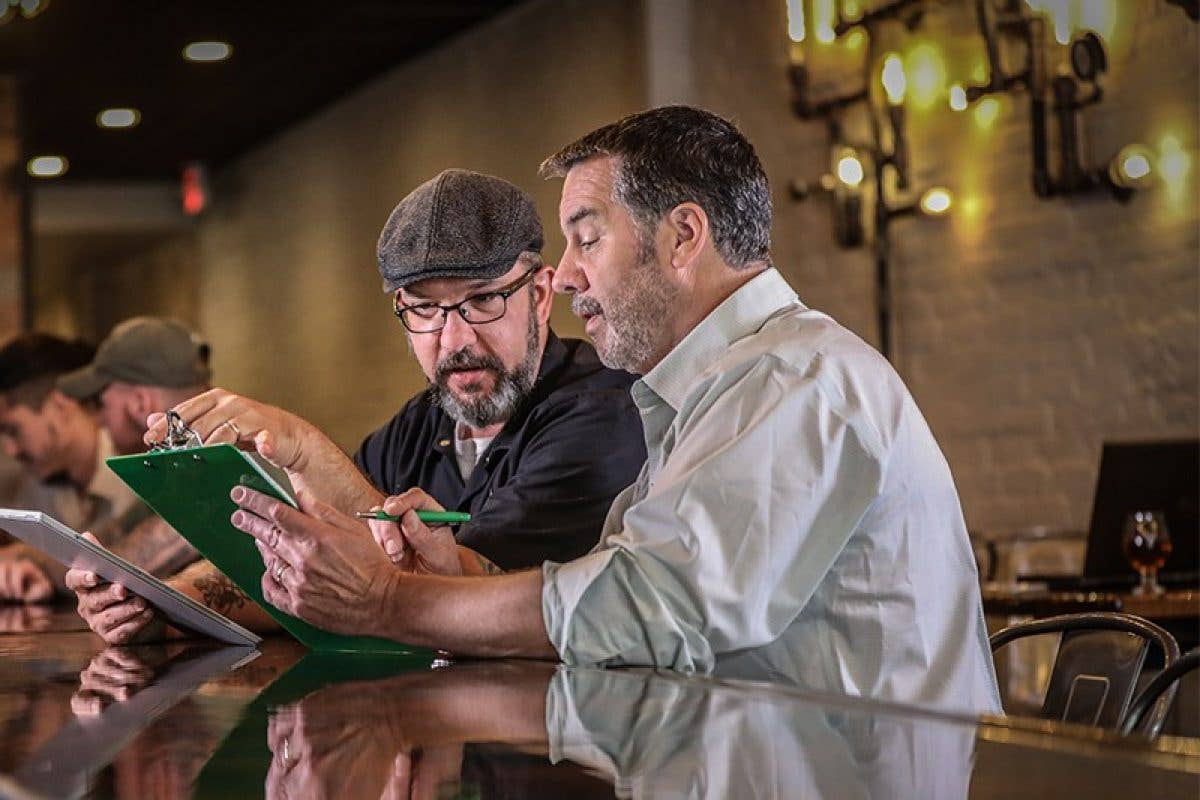 Insurance representative looking at clipboard with man at counter