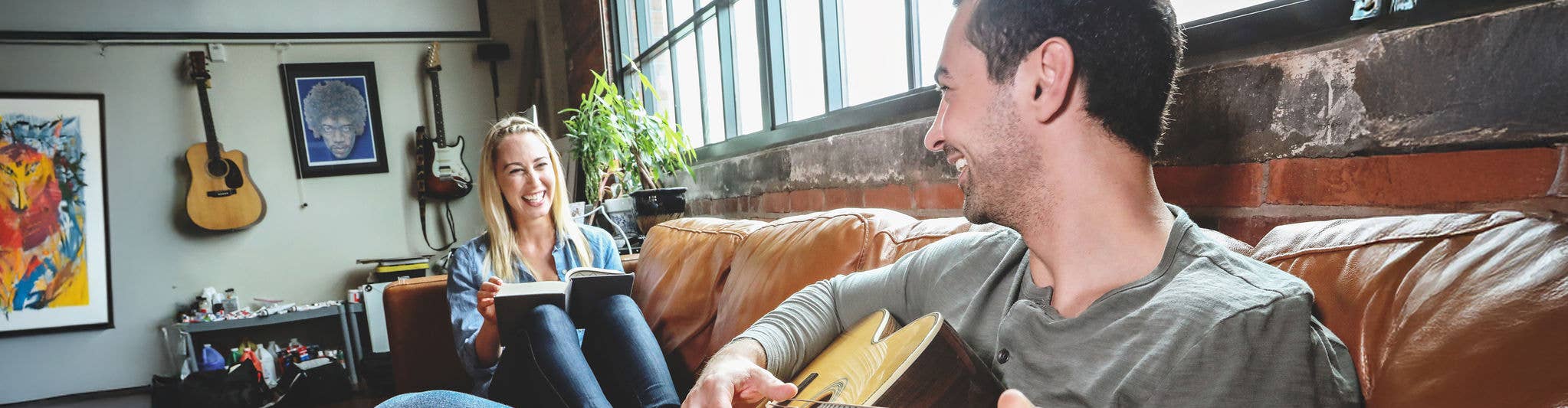 Couple sitting on couch reading and playing guitar