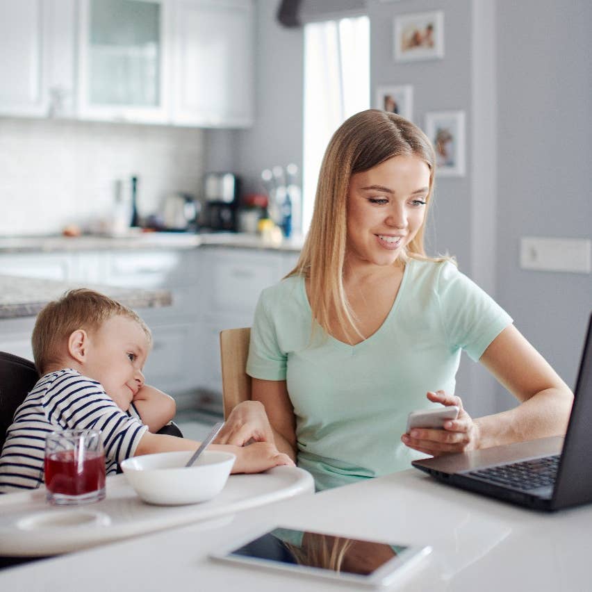 Mother looking at computer, baby in highchair 